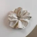 Gedetailleerd overzicht satijnen haarelastiek, elegante crèmekleur en glanzende textuur nabij. - Broken Wit