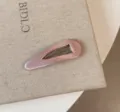 Primo piano fermaglio capelli raso rosa, superficie lucida e solida struttura metallica. - Goccia d'acqua Vuota / Rosa