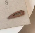 Primo piano del fermaglio per capelli in raso marrone lucido, elegante accessorio quotidiano. - Goccia d'acqua Vuota / Marrone