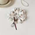 Detailed close up of cute plaid bear print hair scrunchie with brown ribbon and pearl for women daily use. - Cream White Bear Print