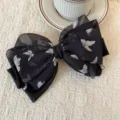 Primo piano dettagliato di un fermaglio per capelli nero in chiffon con farfalle e ciondoli. - Fiocco Stampa Farfalla (Clip a Molla Stampa Farfalla) / Nero