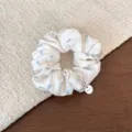 Close-up of sweet Korean pleated scrunchie with blue heart print and metal charm. - Creamy White Heart Polka Dot