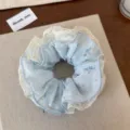Primer plano detallado de un dulce coletero de encaje floral con estampado azul delicado. - Lazo para el Pelo de Encaje Azul