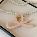 Primo piano del dettaglio della molletta per capelli rosa acrilico con molla dorata. - 11cm / bianco-rosa
