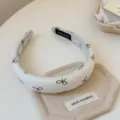 Λεπτομερής κοντινή λευκή υφασμάτινη στέκα μαλλιών με κομψά καφέ φιόγκο σχέδια και καθαρή ραφή. - Πλάτος 3cm / Ζαχαρί