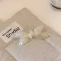 Detalle de pinza de pelo con lazo de acetato blanco perlado exquisito, diseño elegante. - Color Sirena