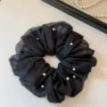 Detaillierte Nahaufnahme schwarzer Chiffon Haargummi mit Perlen, elegantes Haar-Accessoire. - Schwarz