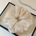 Nahaufnahme des zarten Organza-Haargummis mit künstlichen Perlen, weiche Textur. - Gebrochenes Weiß