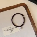 Detail shot of elegant French style dark brown pearl hair tie, minimalist chic accessory. - Dark Coffee