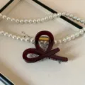 Primo piano dettaglio di molletta per capelli in acrilico rosso scuro con perle su vassoio. - 8cm / Borgogna