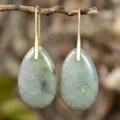 Close-up detail of natural stone teardrop pendant earrings hanging on a rustic branch. - Labradorite