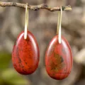 Close-up of red stone teardrop pendant earrings, natural gemstone texture, elegant retro jewelry. - Red Jasper
