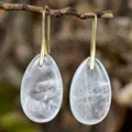 Gros plan détaillé de boucles d'oreilles pendantes en cristal blanc sur fond de bois. - Cristal blanc