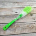 Detailed view of the long handled multi functional cleaning brush with green bristles and handle. - Green