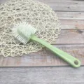 Long handled multi-functional shoe brush with white bristles for household cleaning tasks. - Green