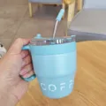 Detailansicht des hellblauen Edelstah-Kaffeebechers mit Strohhalm, Griff und klarem Deckel. - 480ml / Blau
