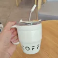 Nahaufnahme eines weißen Edelstahl-Kaffeebechers mit Griff und praktischem Trinkhalm. - 480ml / Weiß
