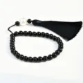 Schwarzes Perlen-Armband mit weißem Akzent und elegantem schwarzen Quasten-Anhänger. - Schwarz