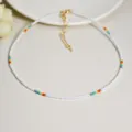 Collana girocollo artigianale di perline di semi bianchi con accenti arcobaleno colorati. - Stile Arcobaleno Bianco (N2554)