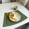 Green waterproof leather placemat with gold stitching for dining table decor and heat insulation. - Embroidered Edge Forest Green