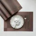 Detailed view of brown woven PVC placemat set on dining table, heat-resistant table mat detail. - Coffee Single Frame