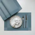 Close-up detail of blue woven placemat set with elegant tableware on tabletop, modern design. - Blue Single Frame