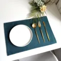 Detailed view of dark green linen textured placemat with white plate and gold cutlery setup. - 45*30cm / Dark Green