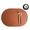 Brown PU leather oval placemat and coaster set with gold cutlery for elegant dining tables. - Placemat 43.5x30cm & Coaster 10cm / Brown and Black