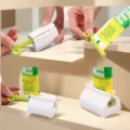 Detail view of white plastic toothpaste squeezer rolling dispenser showing step by step use - Red