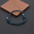 Closeup of handmade adjustable braided rope bracelet with metal tips and minimalist design. - Dark Green