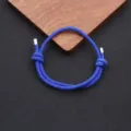 Close-up detail of blue braided rope bracelet with adjustable knot and metal tips. - Blue