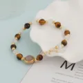 Close-up detail of beaded bracelet featuring tiger eye stones, white beads and golden spacers. - Tiger Eye and White Premium Style