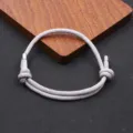 Minimalist grey woven rope bracelet with adjustable knots and metal tips for daily wear. - Gray
