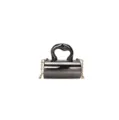 Detailed view of the glossy cylinder handbag highlighting the unique handle and chain strap. - Black