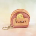 Close-up detail of cute mini pink coin purse keychain with character pendant and chain. - Orange