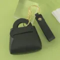 Mini black leather handbag keychain detailed view, featuring gold hardware and wrist strap. - Black