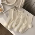 Primer plano detallado de calcetines blancos crema con varios estilos de textura. - Talla única / Borde Ondulado