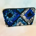 Detailed close-up of a chic black sequin makeup pouch featuring blue geometric designs and pearl zip. - Blue Silver