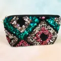 Close-up detail of colorful sequin cosmetic bag zipper and pearl pendant texture showcase. - Blue Glitter