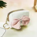 Close-up of holographic coin pouch with large pink satin bow and gold zipper pull detail. - Milky White