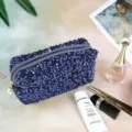 Detailed view of sparkling sequined cosmetic bag in a chic setup with beauty props. - Blue