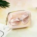 Detailed close-up of the shimmering gradient coin purse with a soft satin bow and keychain. - Pink