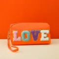 Close-up view of orange cosmetic pouch with colorful textured LOVE letters and wrist strap. - love Series / 18X7X9CM / Heart Orange