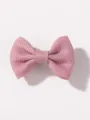 Dettaglio in primo piano della molletta per capelli con fiocco rosa, design grazioso. - Rosa