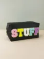 Close-up detail of the black PU makeup pouch featuring colorful chenille STUFF letter patches. - Black (STUFF)