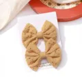 Detailed view of two yellow embroidered fabric bow hair clips with floral patterns on card. - Embroidered Bow Hair Clip (3)