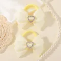 Gedetailleerde close-up van schattige gele haarelastiekjes met strikken en strass harten. - 2 stuks/verpakking / Lichtgeel