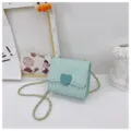 Detailed view of mint green quilted child's purse with heart clasp and chain strap. - Green