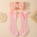 Close-up of pink knit headband and lace socks with decorative satin bows for infants - Three-Piece Set / Pink