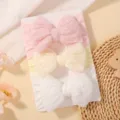 Detail view of three soft baby headbands with large textured lace bows in pastel colors - Pink/Cream/White